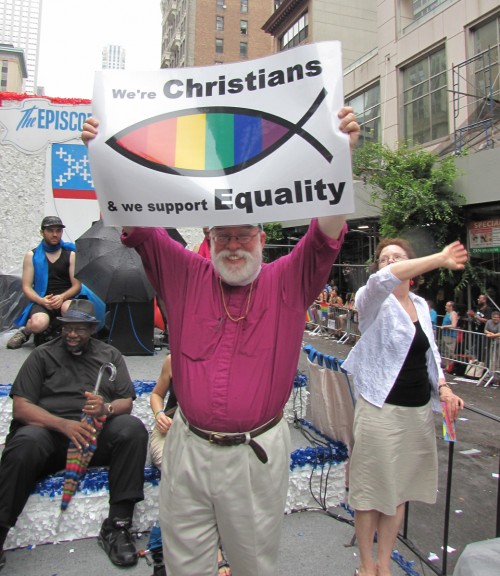 El obispo Andrew M.L. Dietsche, de la Diócesis Episcopal de Nueva York, sostiene una pancarta desde la plataforma de una carroza durante el Desfile del Orgullo Homosexual en Nueva York. Margaret, su esposa, aparece a su izquierda. Foto de Sharon Sheridan para ENS.