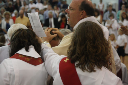 Bishop George Young, along with other clergy members from the East Tennessee and surrounding areas, lays his hands on the Rev. Joshua Ashton Hill during the service. Photo: Episcopal School of Knoxville