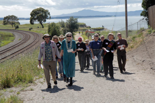 The Rev. Susan Champion, rector of Christ the Lord Episcopal Church, Pinole, leads more than 25 participants in the April 23 EcoConfirmation on a journey to the communion table, stopping for prayers at three points along the way where beauty and degradation meet. She and her husband, the Rev. Peter Champion, live in Rodeo. Photo: Lynette Wilson/Episcopal News Service 