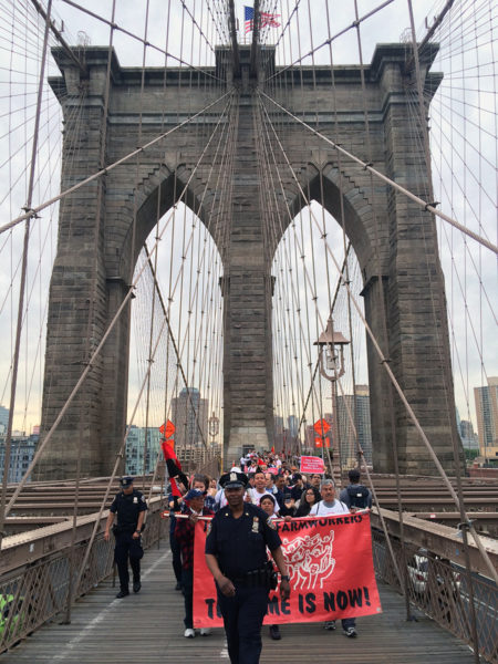 A New York City police officer leads marchers across the Brooklyn Bridge into Manhattan on May 21. Photo: Amy Sowder 