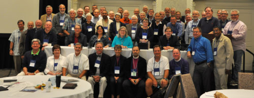 n a break with the practice in the recent past, House of Deputies President the Rev. Gay Clark Jennings, center behind table in aqua, was invited to join the House of Bishops for its entire Sept. 15-20 meeting in Detroit. She spoke to the bishops on more than one occasion during the meeting and officiated at Morning Prayer on Sept. 20. Here she poses with all of the bishops present who had served as deputies before their election as bishops. Photo: Mary Frances Schjonberg/Episcopal News Service