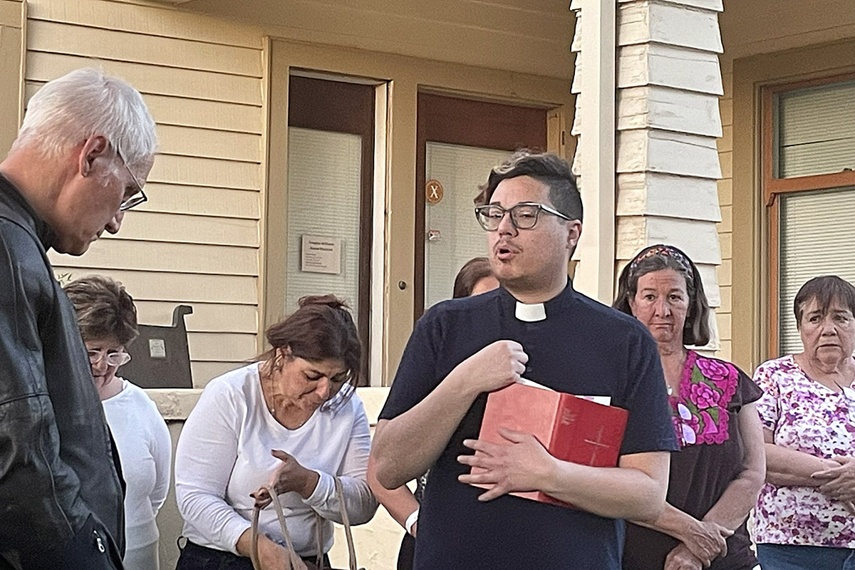 The Rev. John Caleb Collins, vicar of St. Stephen’s, leads a prayer on the evening of the fire across the street from the burned church. Photo: Jennifer Reddall